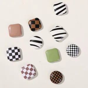 Close-up of decorative square and round buttons with checkerboard and cow patterns for DIY