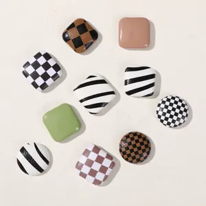 Detailed view of various checkerboard and cow pattern DIY buttons for hair accessories