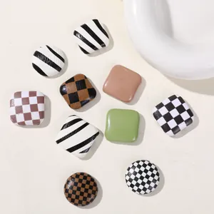 Close-up view of checkerboard and striped square DIY decorative buttons for hair accessories