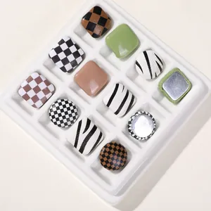 Detailed view of assorted checkerboard and cow print buttons arranged in a white grid tray