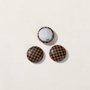 Detail view of small round buttons with brown and black checkered pattern and silver back