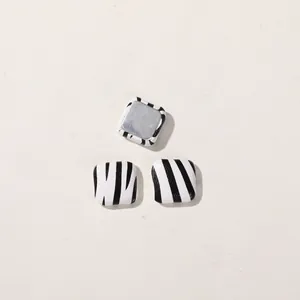 Close-up of square cow print DIY buttons showing patterned front and metal flat back.