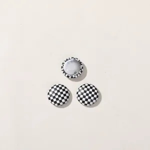 Close-up of round black and white checkerboard DIY buttons with silver metal back