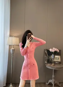 Detailopname van een elegante roze gebreide jurk met V-hals en parelmoer knopen