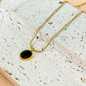 Dettaglio collana dorata con pendente ovale in pietra occhio di gatto nera