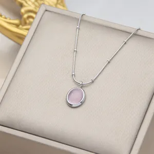 Primo piano di una collana in argento con pendente ovale in pietra occhio di gatto rosa.