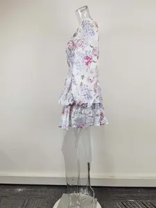 Detailed side view of a white floral print lantern sleeve tiered dress on a clear mannequin
