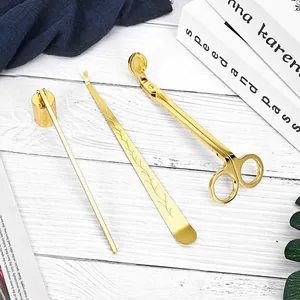 Elegant 3-piece gold stainless steel candle accessory set on white wood background