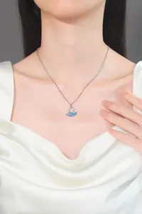 Close-up detail of a silver heart necklace featuring blue wave crystal inlay on a model
