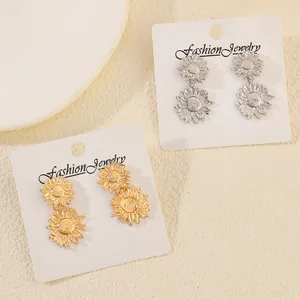 Detailed view of gold and silver sunflower drop earrings on white jewelry cards