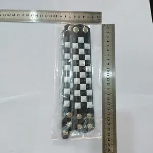 Close-up of black and white studded punk bracelet with ruler for size reference