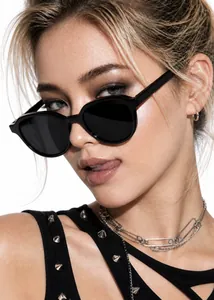 Detail shot of vintage black oval sunglasses worn by a stylish model in high fashion.