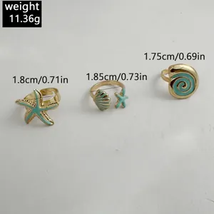 Détail de trois bagues dorées sur le thème de l'océan avec émail turquoise et tailles