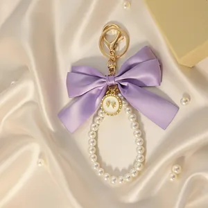 Detailed view of an elegant purple satin bow and pearl bead keychain with gold hardware