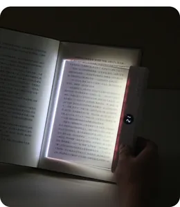 Close-up of portable LED flat reading light panel illuminating a book in the dark