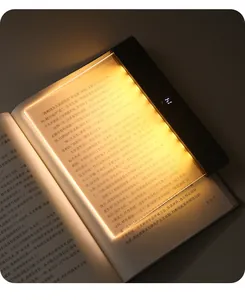 Detail of portable flat panel reading light illuminating a book page with warm glow
