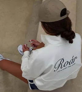Back view detail of a white half-zip sweatshirt featuring 'Roar' graphic print design.
