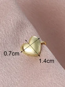 Detailed macro view showing a gold-toned heart-shaped ear cuff with dimension markings