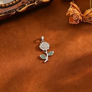 Macro view of a delicate silver rose pendant with micro-paved zircons and green leaves
