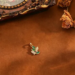 Detailed view of micro-pave zircon leaf pendant with green stones and 18k gold plating.