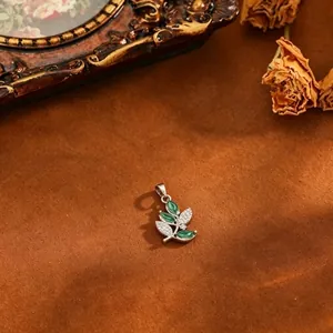 Detailed close-up of an elegant leaf pendant with green gemstones and zircons on brown velvet