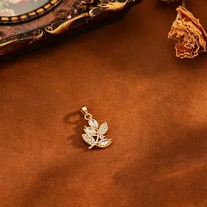 Macro view of a 18k gold plated leaf pendant with sparkling cubic zirconia inlay.