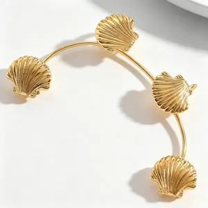 Dettaglio ravvicinato di ciondoli a conchiglia dorati su un ear cuff stile oceano elegante