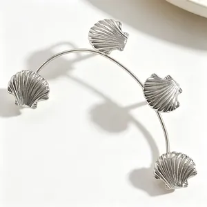 Dettaglio di un ear cuff argento con quattro delicati motivi a conchiglia su bianco