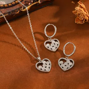 Détail macro d'un ensemble collier et boucles d'oreilles cœur en acier avec perles.