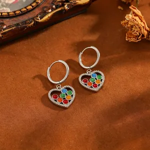 Gros plan de boucles d'oreilles créoles en acier avec cœur perlé et pavé de zircon.