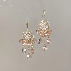 Orecchini bohémien in oro con cristalli rosa e design geometrico a nappa.