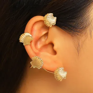 Primo piano di un elegante ear cuff a forma di conchiglia dorata indossato su un modello