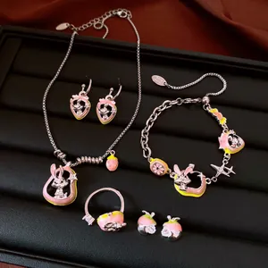 Detailed view of a jewelry set featuring rabbit and fruit enamel designs in pink and yellow.