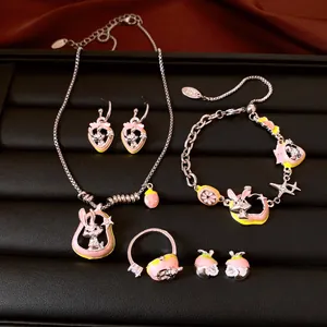 Detailed macro shot of a cute pink rabbit and strawberry enamel jewelry set on black display