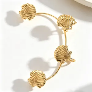 Dettaglio di un ear cuff a conchiglia dorato con texture raffinate e design ispirato al mare