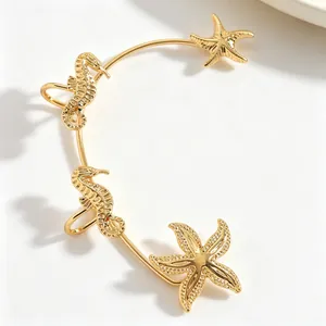 Dettaglio di un earcuff dorato a tema marino con motivi di cavallucci e stelle marine
