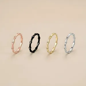 Dettaglio di quattro anelli geometrici in acciaio inossidabile in oro, argento, rosa e nero.