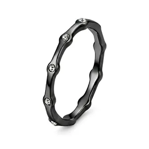 Primo piano di un anello minimalista ondulato in acciaio inossidabile nero con cristalli.