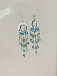 Detailansicht von Silbernadol-Quastenohrringen mit türkisen und blauen Kristallen.