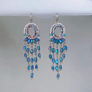 Nahaufnahme von Kristall-Quastenohrringen im Ethno-Stil mit funkelnden blauen Perlen.