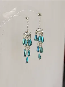 Detailansicht langer Quastenohrringe mit blaugrünen Kristallen und klarem Strass.
