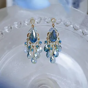 Makroansicht von blauen Kristall-Quastenohrringen in Tropfenform mit goldenen Akzenten