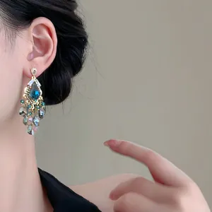 Nahaufnahme von eleganten blauen Kristall-Quastenohrringen mit Strasssteinen am Modellohr