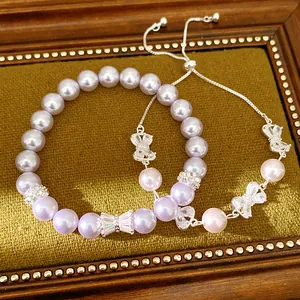 Detail of purple pearl bracelets with zircon bow charms on vintage velvet tray.