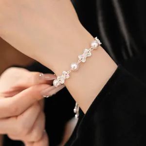 Close-up of elegant zircon bowknot pearl bracelet on wrist with black velvet sleeve
