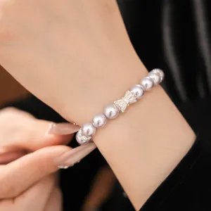 Detailed macro view of a beaded lavender pearl bracelet with sparkling zircon bow on a wrist