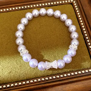 Elegant close-up of a lavender pearl bracelet featuring a sparkly zircon bow charm.
