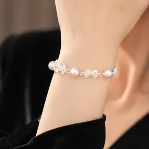 Elegant silver zircon bow and pearl bead bracelet worn on wrist showing intricate details