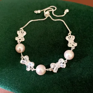 Macro view of exquisite pearl and zircon bow bracelet on dark green velvet background