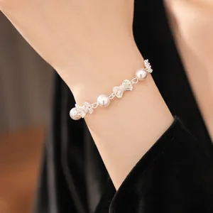 Close-up detail of an elegant pearl bracelet featuring sparkling zircon bow charms.